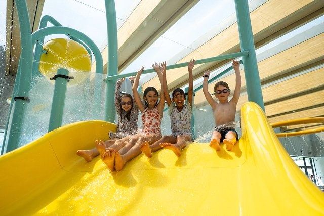 Child and father sliding down yellow waterslide at Gunyama Park