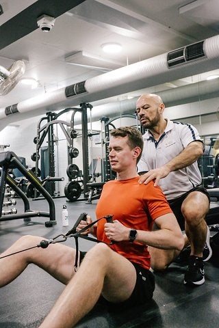 Personal trainer providing support to participant using suspension bands at Cook + Phillip Park Pool