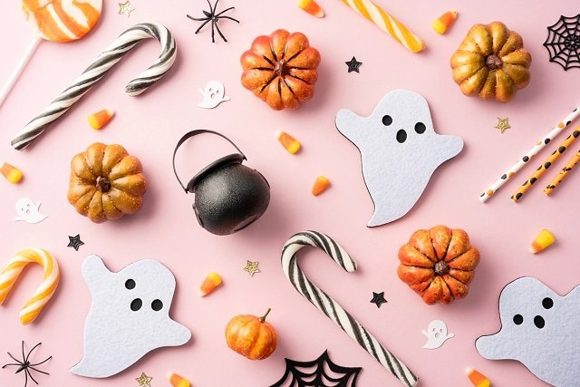 A flat lay of Halloween props including pumpkins and paper ghosts 