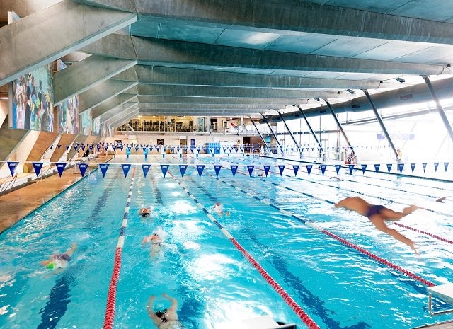 People diving and swimming in the indoor 50m pool at Cook + Phillip Park Pool.