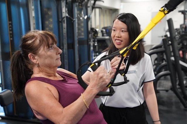 Exercise physiologist guides participant to stretch using resistance band