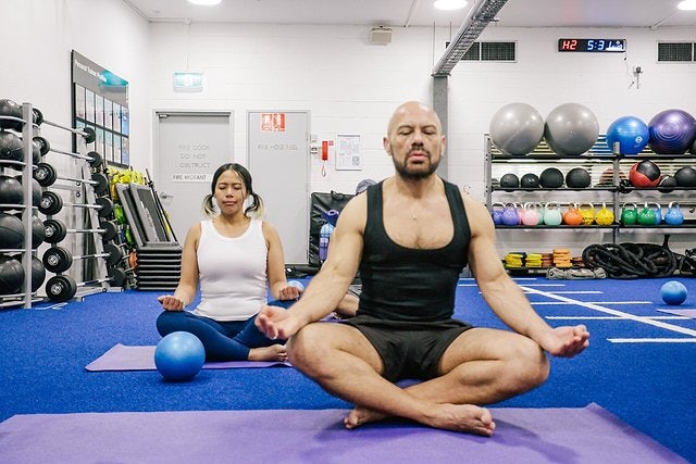 Male and female meditating on the gym floor at Cook + Phillip Park Pool