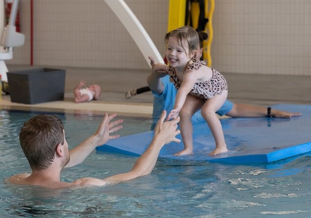 Child jumping towards her father in the pool during a swim lesson