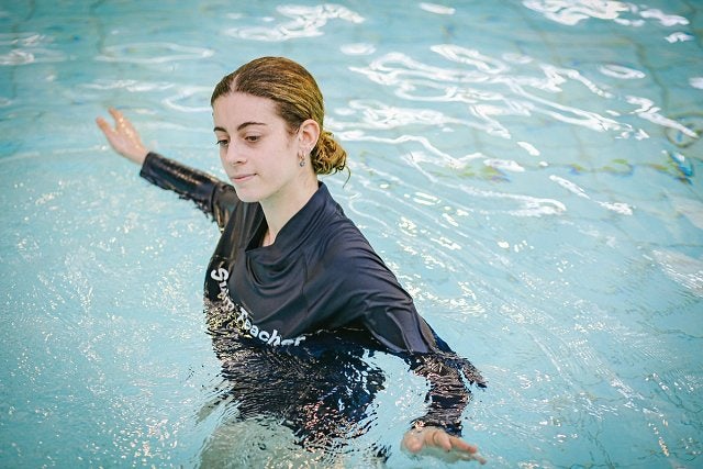 Learn to swim instructor demonstrating a swimming stroke in the program pool