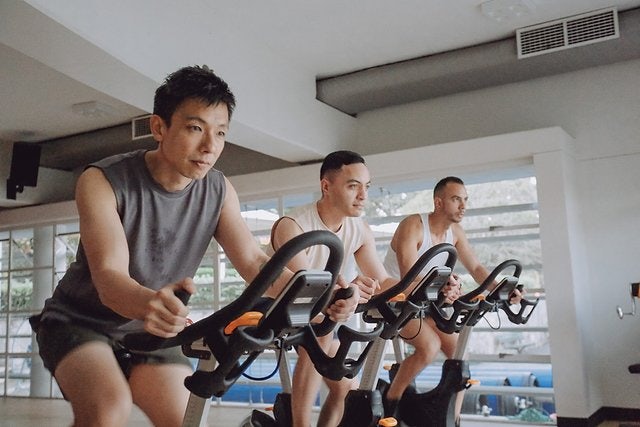 Three men exercising on bikes during a group exercise class at Victoria Park Pool