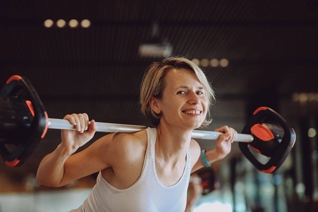 Female smiles while performing a dumbbell squat