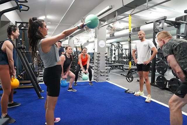 Group of people using kettle bells on the gym floor to exercise at Cook + Phillip gym